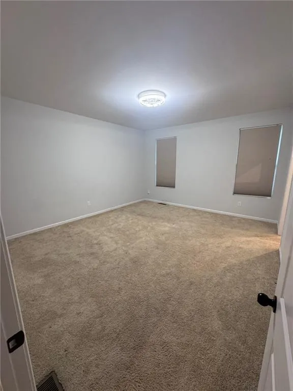Empty room featuring light carpet and baseboards