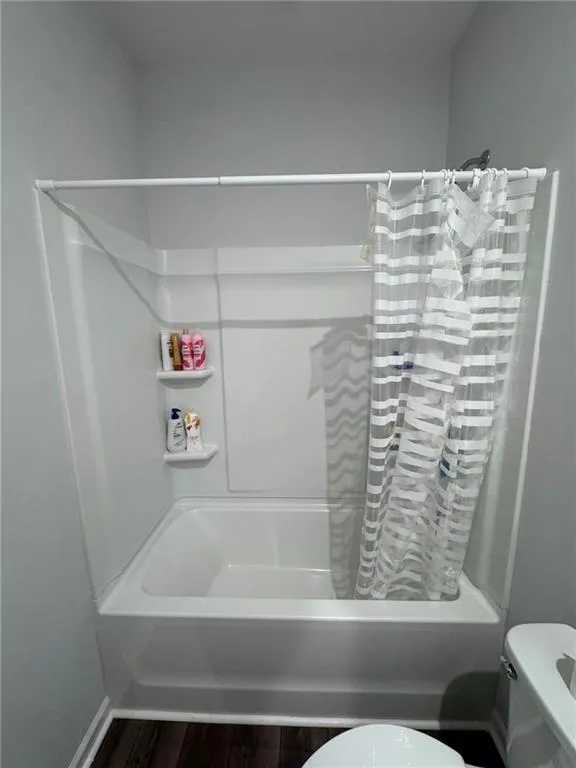 Bathroom with shower / tub combo and dark wood-style floors