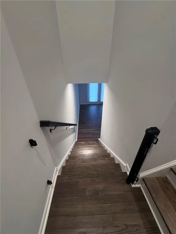 Stairway with wood finished floors and baseboards