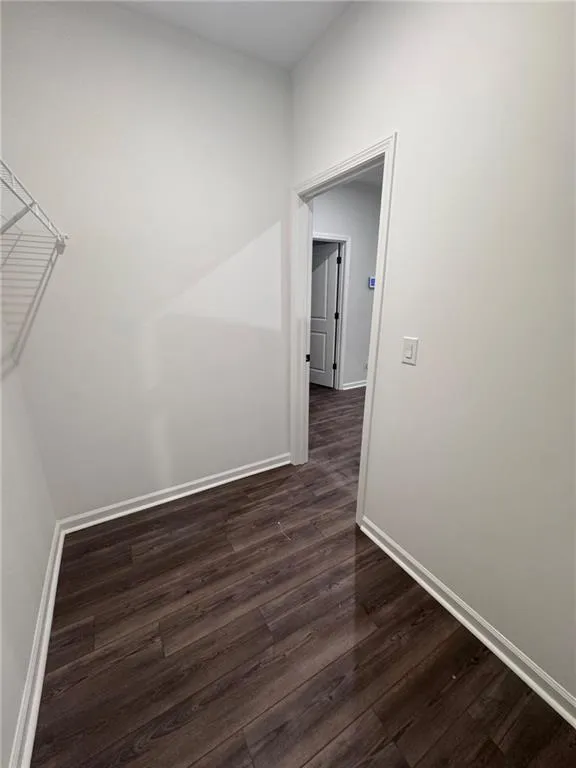 Unfurnished room featuring baseboards and dark wood finished floors