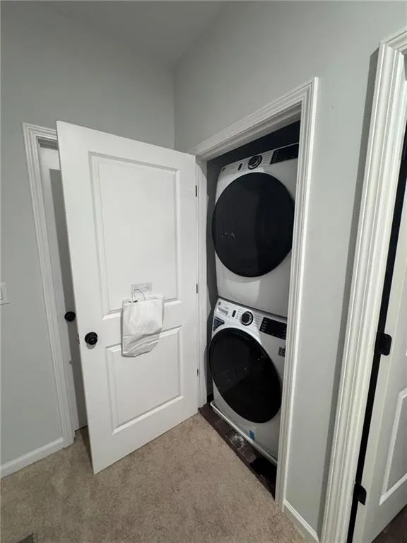 Washroom with stacked washer / drying machine and carpet flooring