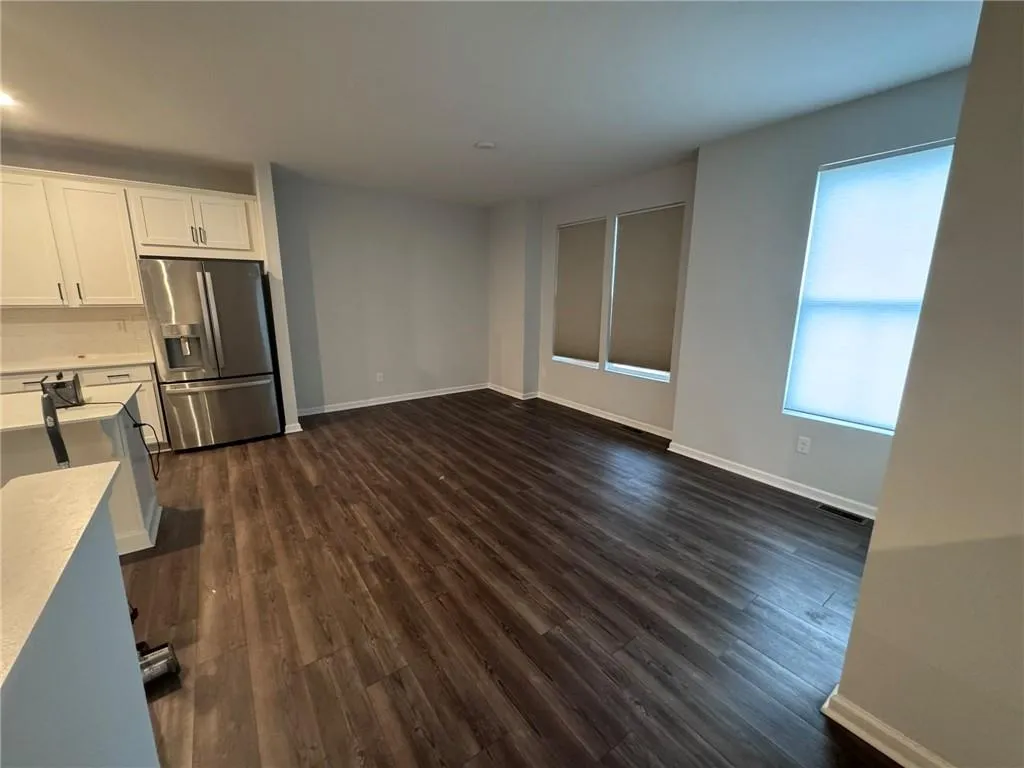 Kitchen with white cabinetry, stainless steel fridge with ice dispenser, dark wood finished floors, and tasteful backsplash