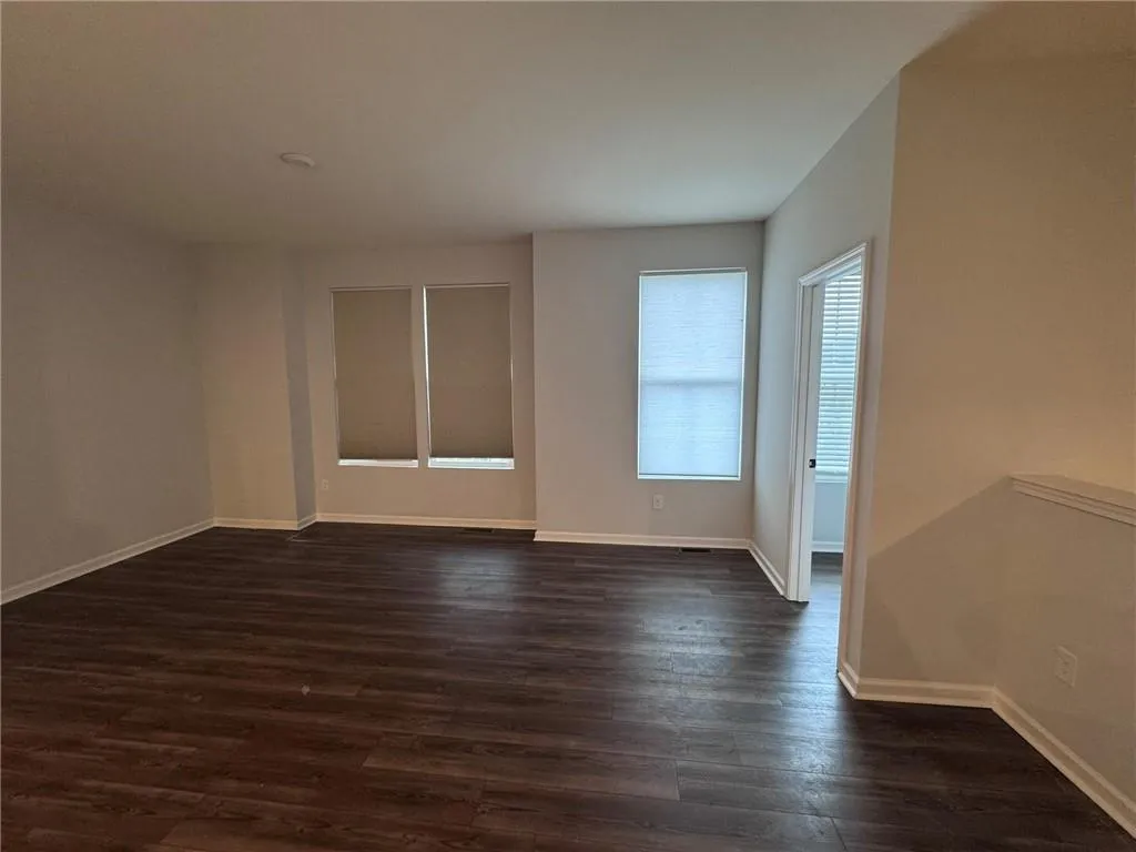Empty room featuring baseboards and dark wood-style flooring