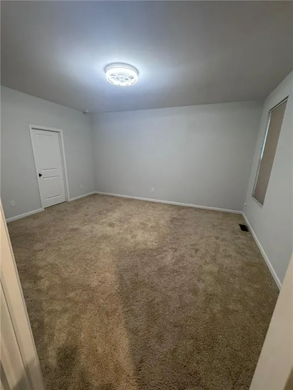 Unfurnished room featuring light colored carpet and baseboards
