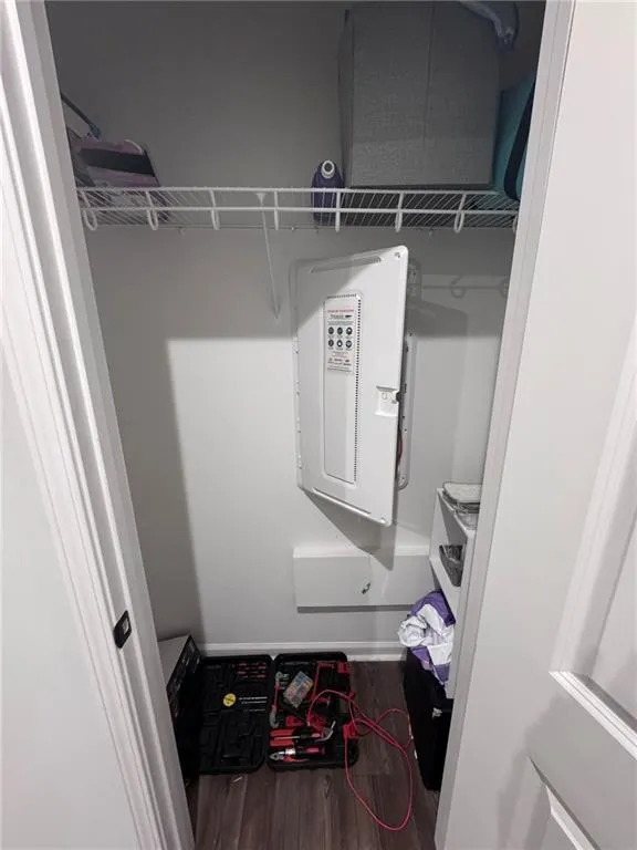 Walk in closet with dark wood-style flooring
