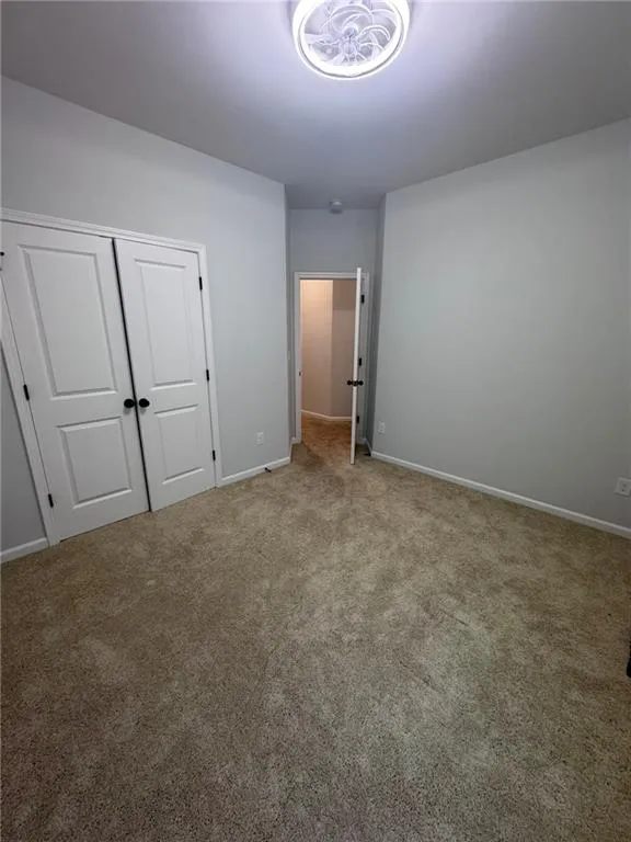 Unfurnished bedroom featuring carpet and a closet
