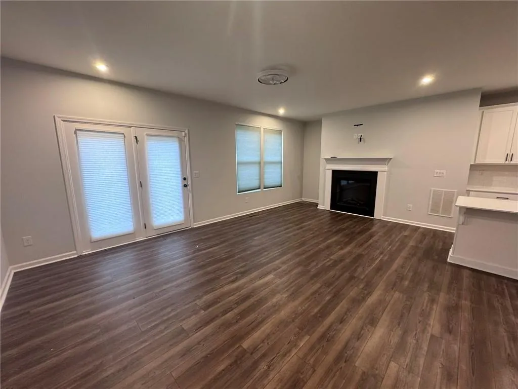Unfurnished living room featuring a glass covered fireplace, recessed lighting, and dark wood-style flooring
