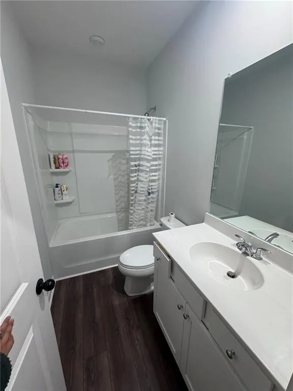 Full bathroom featuring shower / tub combo with curtain, dark wood finished floors, and vanity