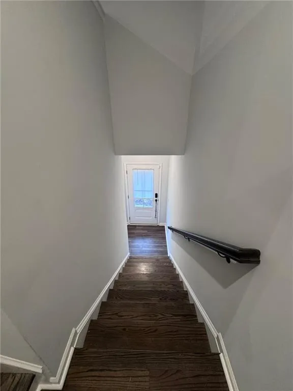 Staircase with wood finished floors and high vaulted ceiling