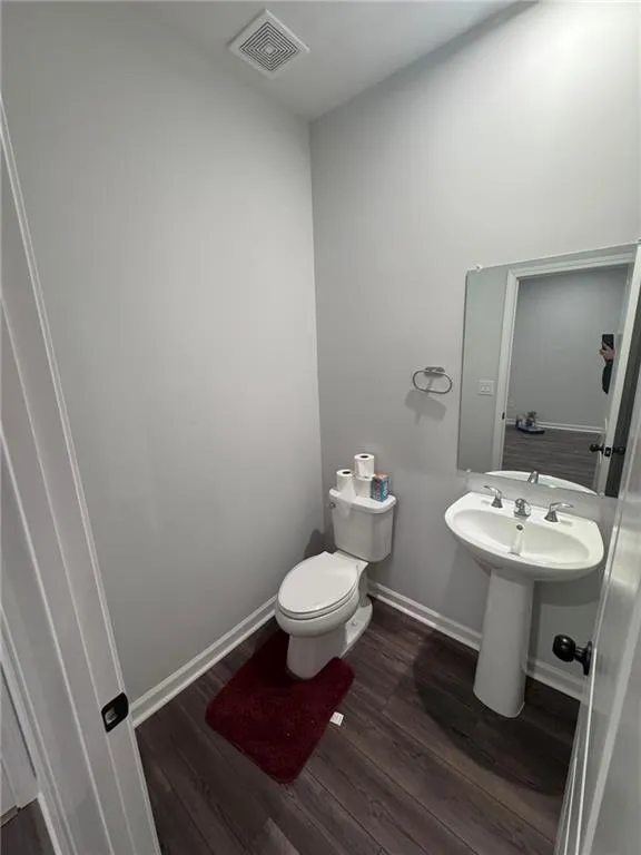 Half bathroom featuring baseboards and dark wood-style floors
