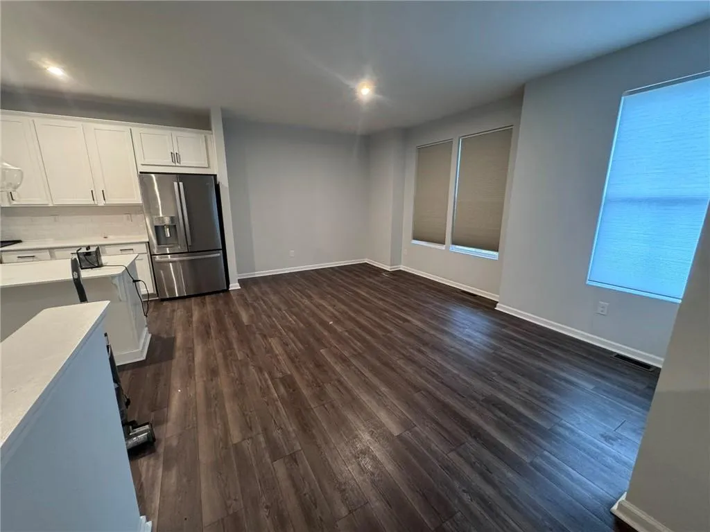 Kitchen featuring white cabinets, stainless steel fridge with ice dispenser, dark wood-type flooring, and tasteful backsplash