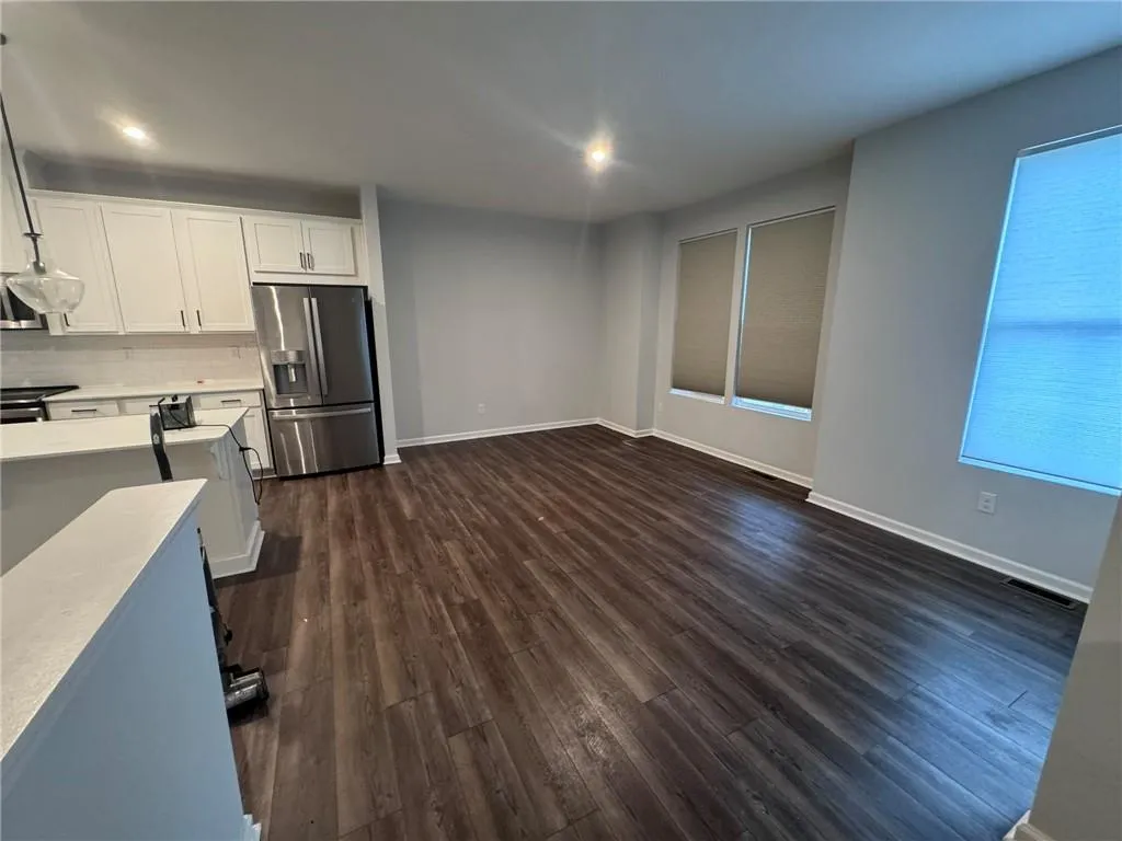 Kitchen with white cabinetry, stainless steel appliances, dark wood-style floors, and tasteful backsplash