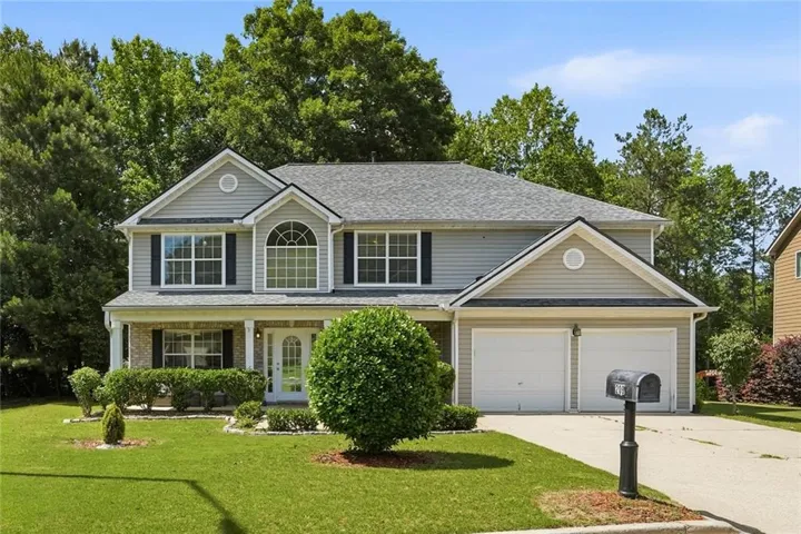 Two-story residence featuring light gray siding, white trim, and a prominent front gable with an arched window