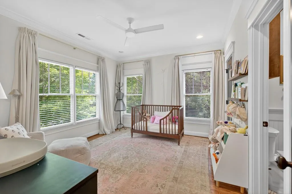 Hardwood flooring, crown molding, white ceiling fan, multiple windows with blinds, and built-in shelving
