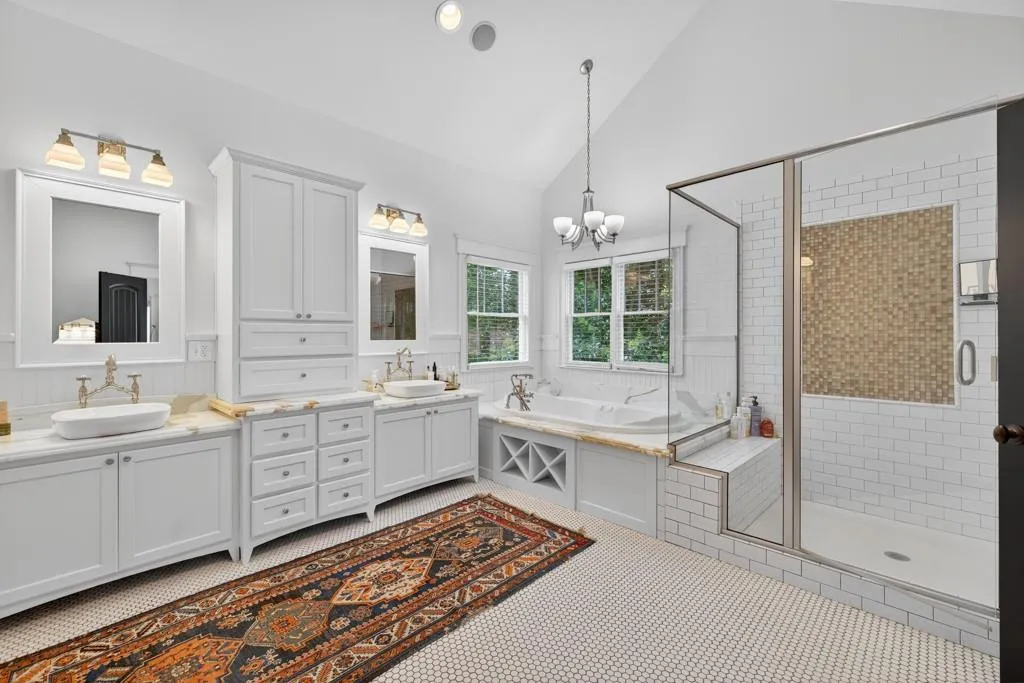 Dual vanity with vessel sinks, white shaker cabinetry, and built-in soaking tub