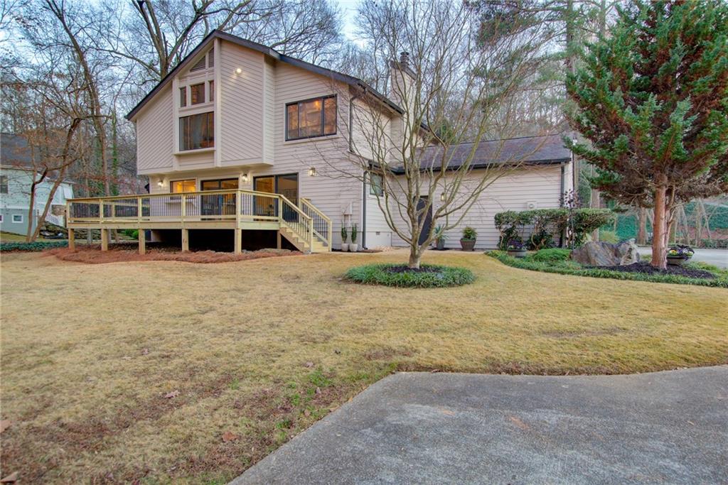 Back of house featuring a lawn and a deck