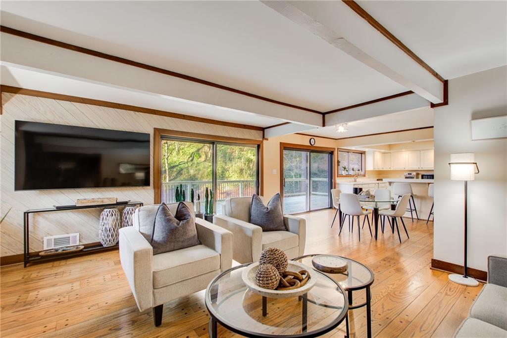 Great room opens to kitchen  with beam ceiling and hardwood  flooring.