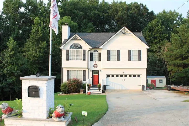 White siding exterior with black shutters, arched window, attached two-car garage, and a red front door