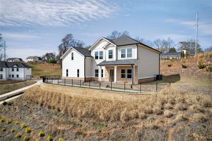 Contemporary two-story residence featuring a mixed-material facade with white board-and-batten and horizontal siding, stone accents, and dark-framed windows