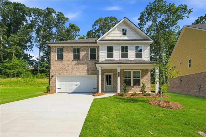 Two-story residence featuring brick and shaker siding, a two-car garage, and a covered front entry supported by white columns
