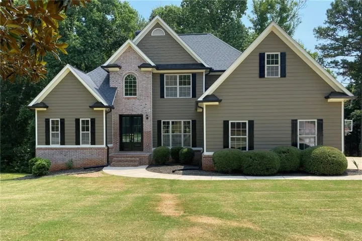 Two-story residence featuring a brick and siding facade, a dark shingle roof, and multiple gables