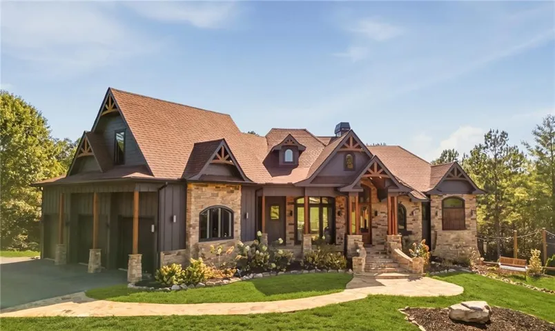 Craftsman-style home featuring a stone and board-and-batten exterior, multi-gabled roofline, covered front entry, and attached garage
