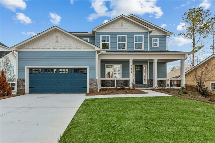 Craftsman house featuring stone siding, covered porch, concrete driveway, and a front lawn