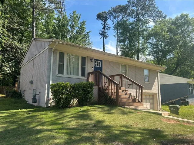 View of front of property featuring an attached garage, brick siding, and a front lawn