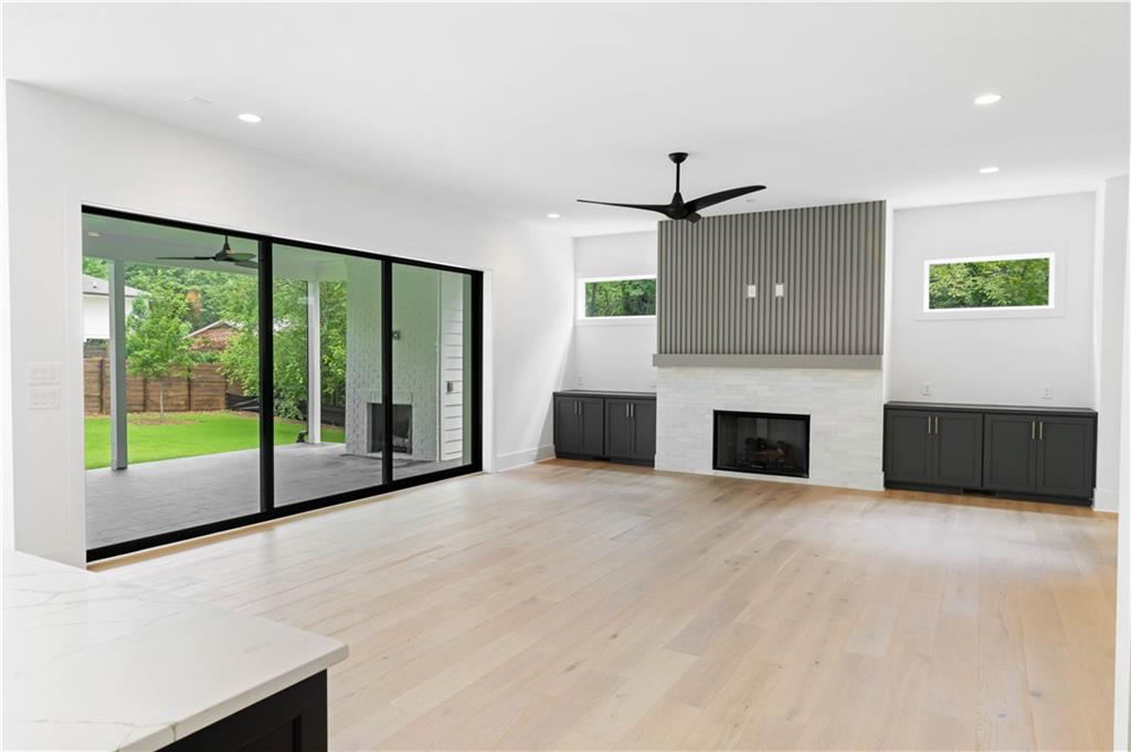 The expansive family room features custom built-ins, an inviting fireplace with a tile/wood accent surround, and western sliding doors leading to the covered outdoor lounge.