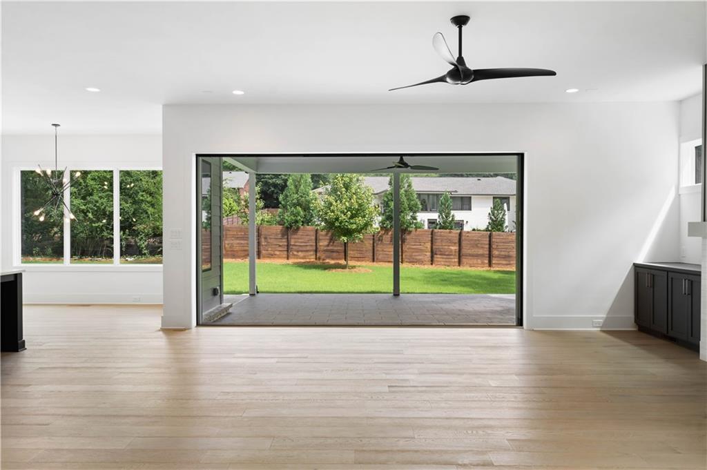 The expansive family room features custom built-ins, an inviting fireplace with a tile/wood accent surround, and western sliding doors leading to the covered outdoor lounge.