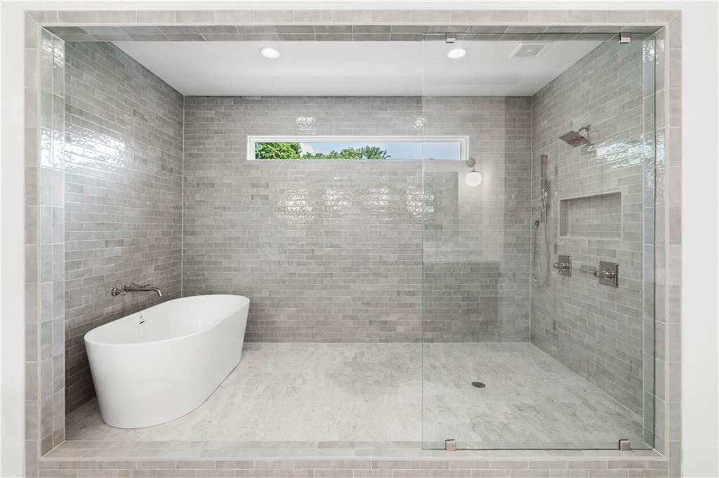 Spa-like bathroom featuring an awe-inspiring wet room with impeccable tile details, a soaking tub, double vanity, large custom closets, and a private water closet.