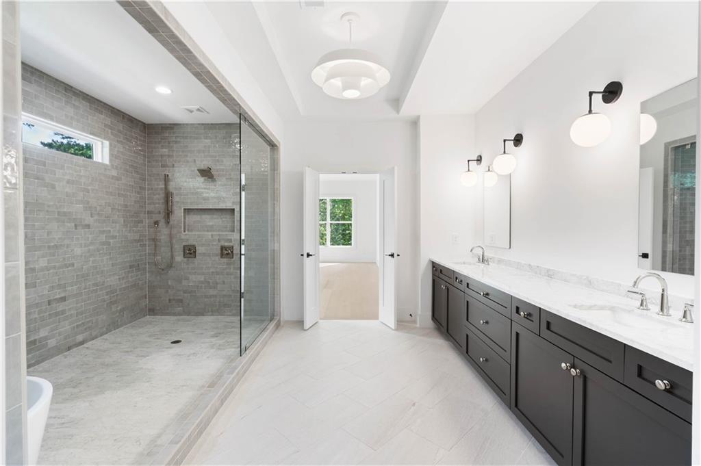 Spa-like bathroom featuring an awe-inspiring wet room with impeccable tile details, a soaking tub, double vanity, large custom closets, and a private water closet.
