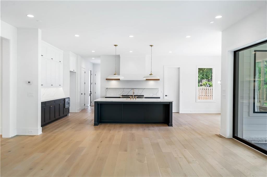 The chef's kitchen is a masterpiece, boasting custom shaker cabinetry with soft-close doors, a quartz backsplash, high-end stainless steel appliances, a custom range hood, and a breakfast area.