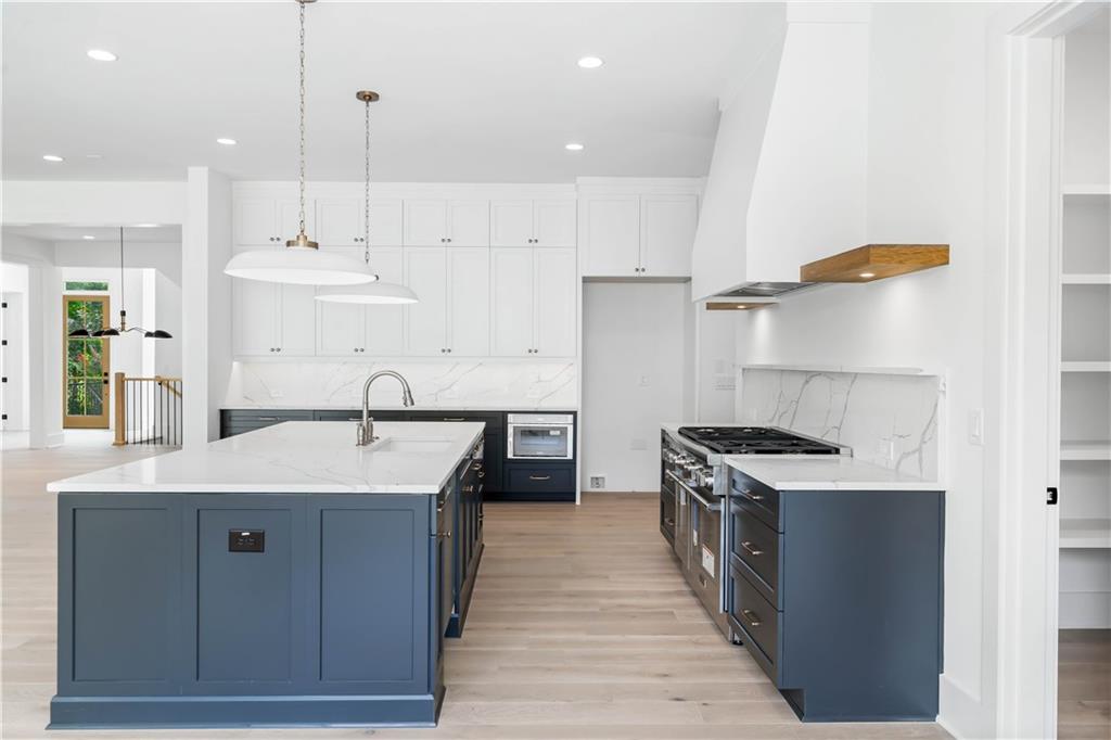 The chef's kitchen is a masterpiece, boasting custom shaker cabinetry with soft-close doors, a quartz backsplash, high-end stainless steel appliances, a custom range hood, and a breakfast area.