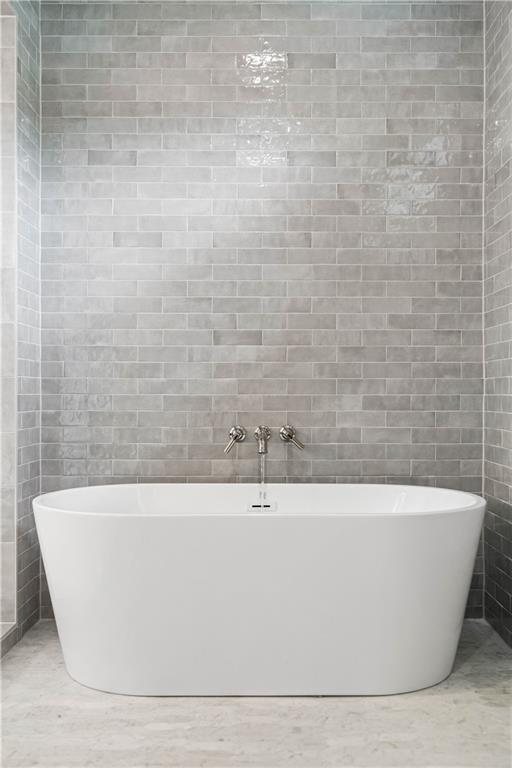Spa-like bathroom featuring an awe-inspiring wet room with impeccable tile details, a soaking tub, double vanity, large custom closets, and a private water closet.