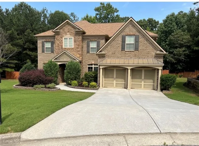 Traditional two-story residence with a brick and stone facade, featuring a prominent two-car garage with arched entries