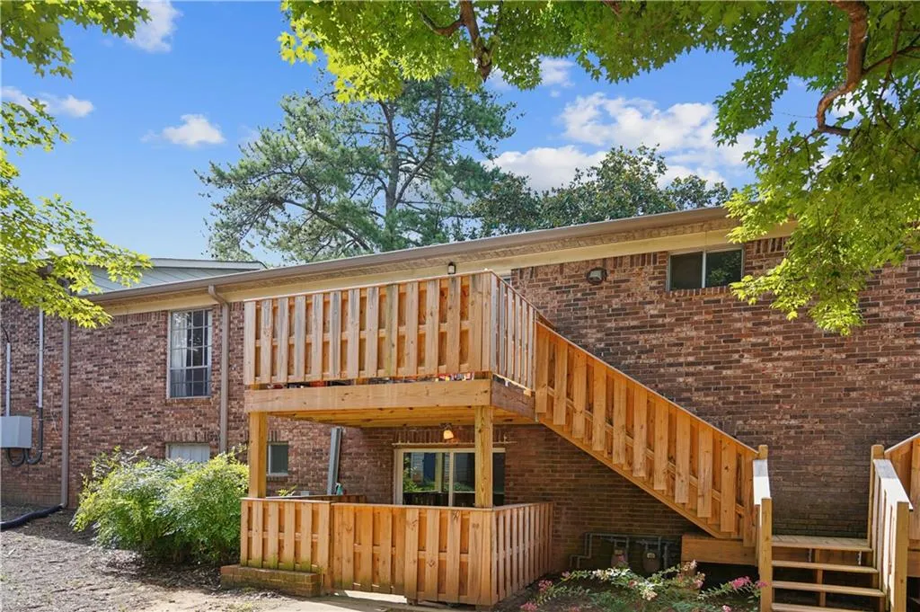 Rear view of property with brick siding, a deck, and stairs