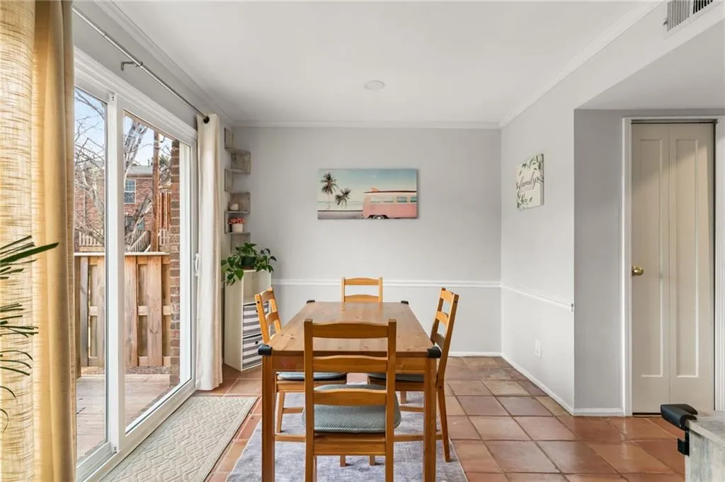 Dining area featuring tile patterned floors, baseboards, visible vents, and ornamental molding