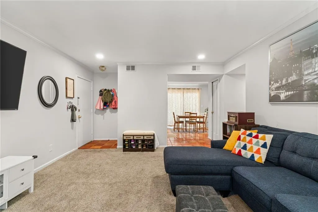 Carpeted living room featuring visible vents, recessed lighting, baseboards, and ornamental molding