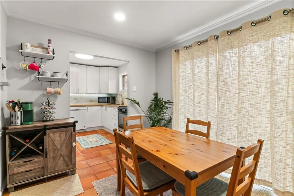 Dining area with light tile patterned floors and crown molding