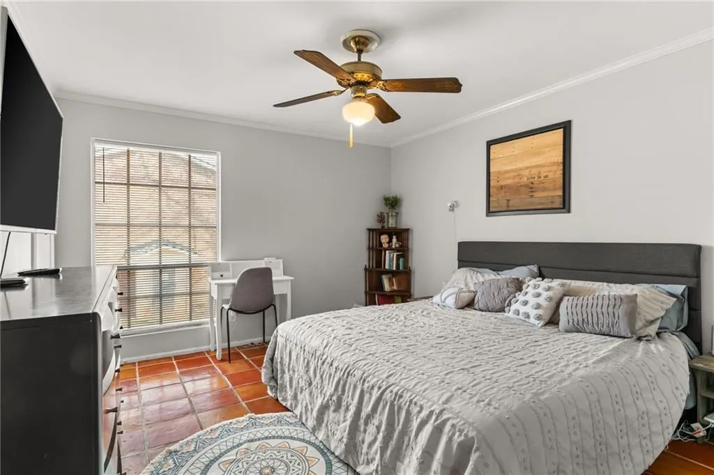 Bedroom with ceiling fan, light tile patterned flooring, and ornamental molding