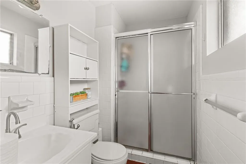 Bathroom with vanity, tile walls, toilet, and a stall shower
