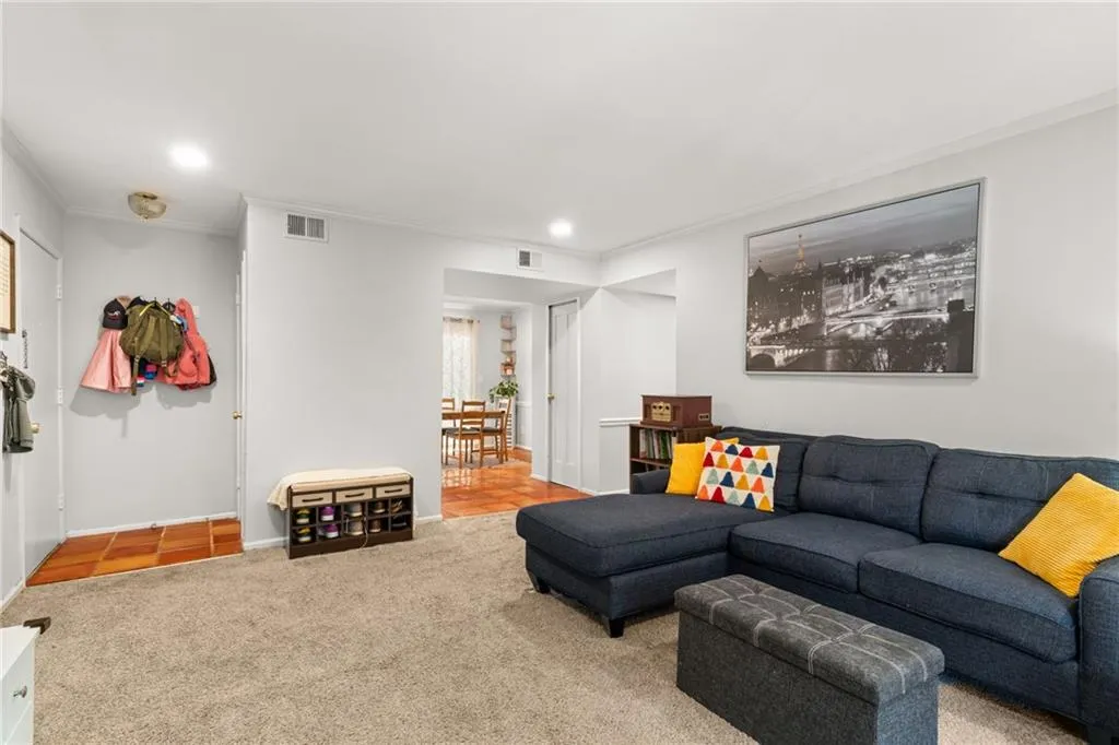 Carpeted living room featuring visible vents, recessed lighting, baseboards, and ornamental molding