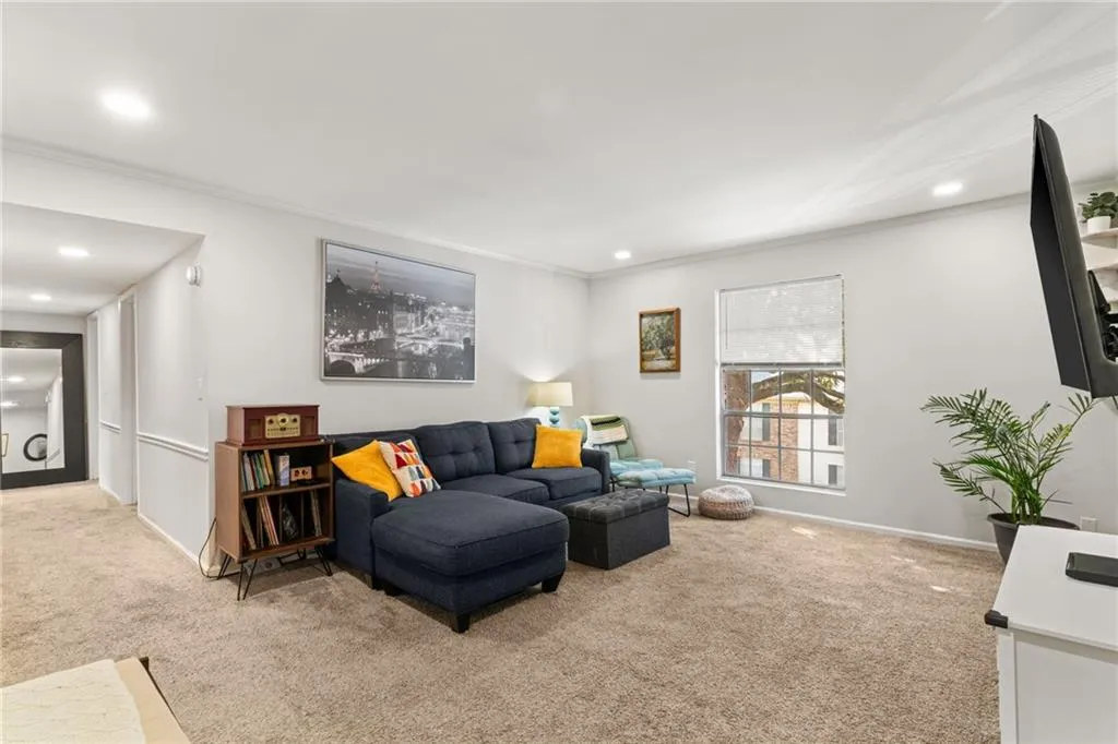 Living room featuring recessed lighting, light colored carpet, crown molding, and baseboards