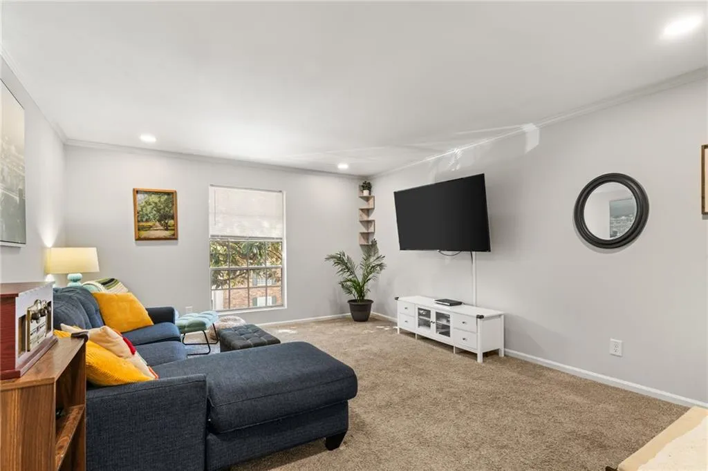 Carpeted living area with crown molding, recessed lighting, and baseboards