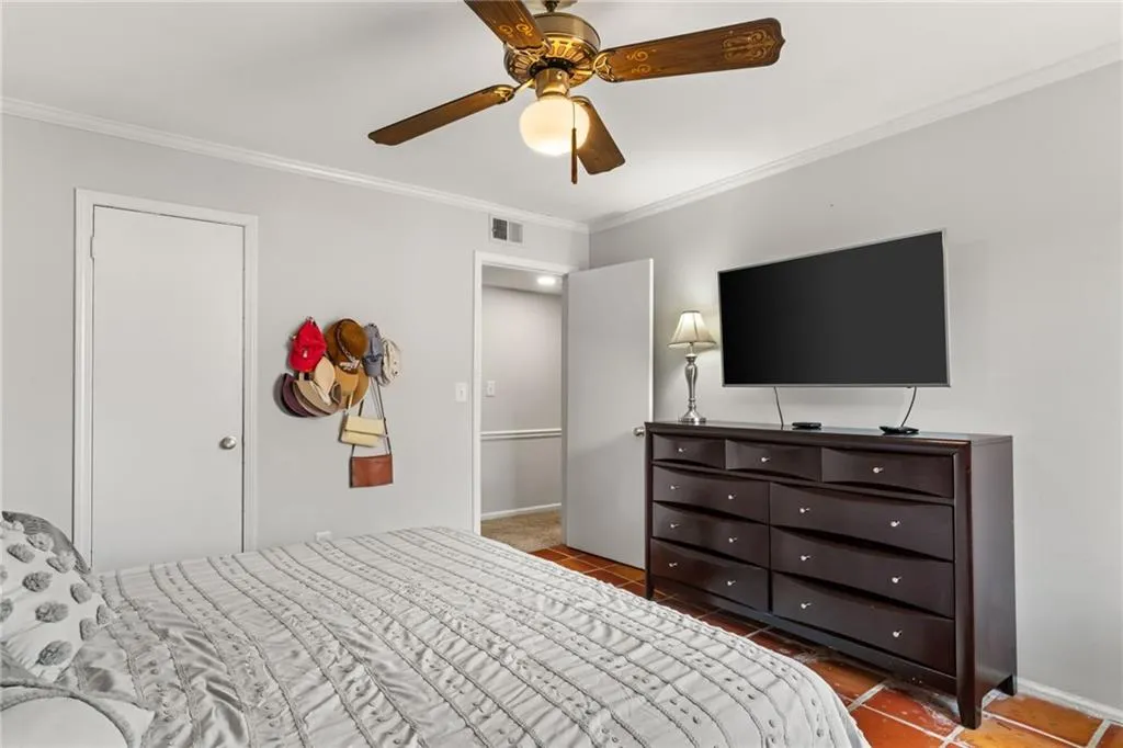 Bedroom with visible vents, baseboards, ceiling fan, and ornamental molding