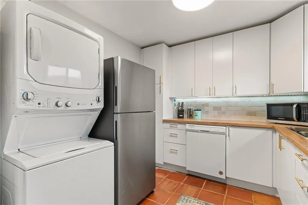 Washroom featuring laundry area, light tile patterned flooring, and stacked washer and clothes dryer