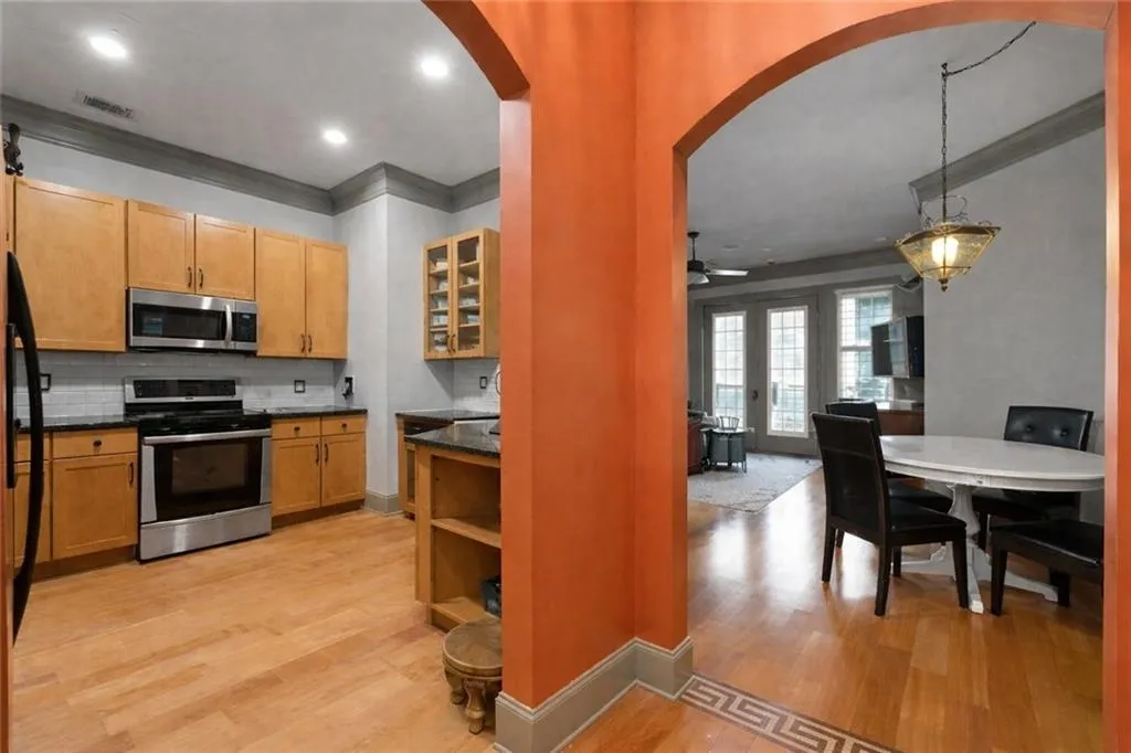 Kitchen with glass insert cabinets, stainless steel appliances, crown molding, tasteful backsplash, and dark stone countertops