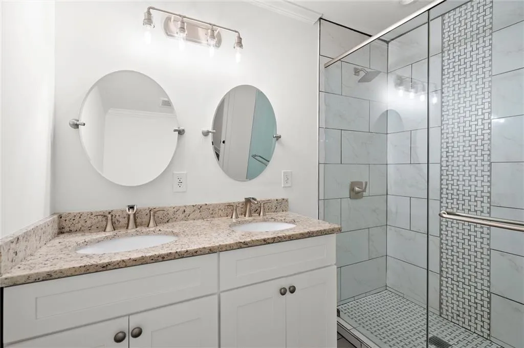 Bathroom featuring double vanity, a stall shower, and crown molding