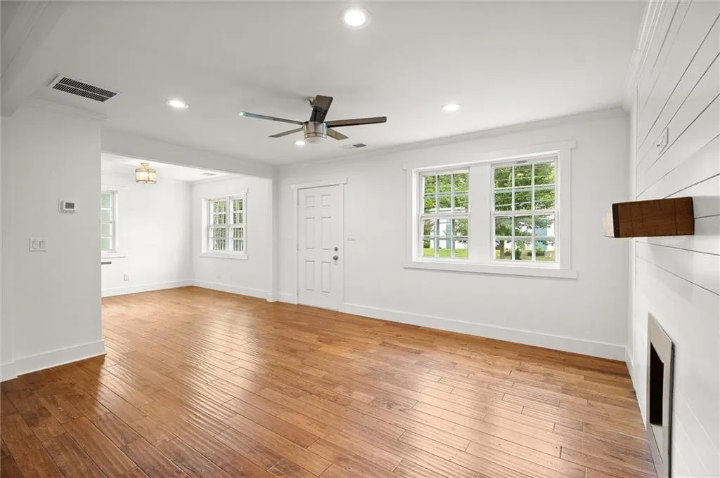 Unfurnished living room with crown molding, ceiling fan, light wood-style floors, a large fireplace, and recessed lighting